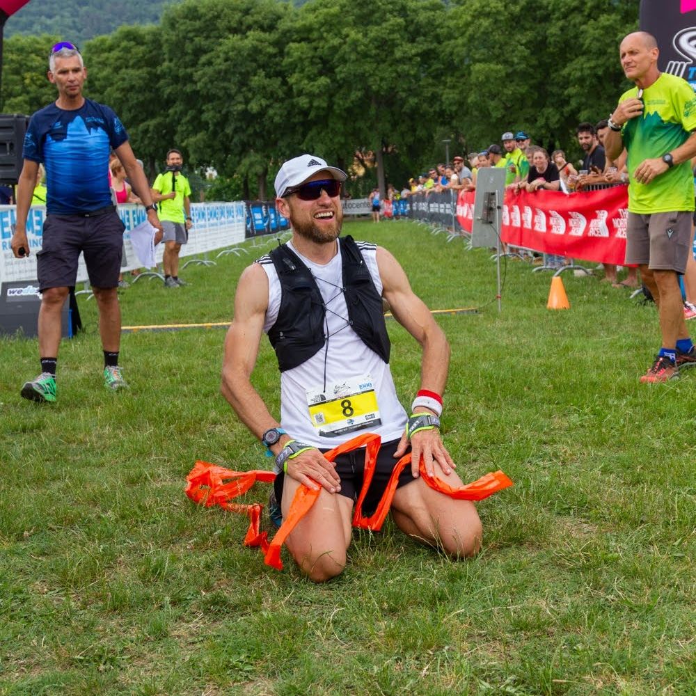 Arrivo di una gara trail, atleta inginocchiato sul traguardo